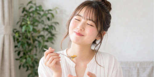はちみつを食べて甘くて美味しいと思っている若い女性