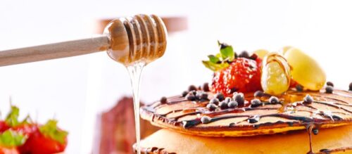ハニーディッパーではちみつをパンケーキにかけている